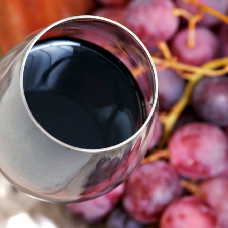 Glass of red wine with grapes.